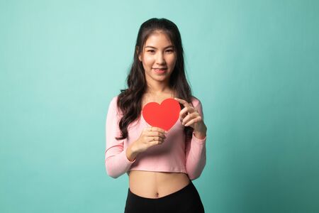 Asian woman with red heart on cyan backgroundの写真素材