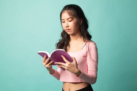 Young Asian woman read a book on cyan backgroundの写真素材