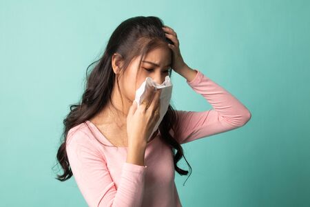 Young Asian woman got sick and flu on cyan backgroundの写真素材