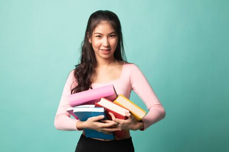 Young Asian woman studying  with may books on cyan backgroundの写真素材