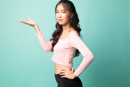 Young Asian woman present with her hand on cyan backgroundの写真素材