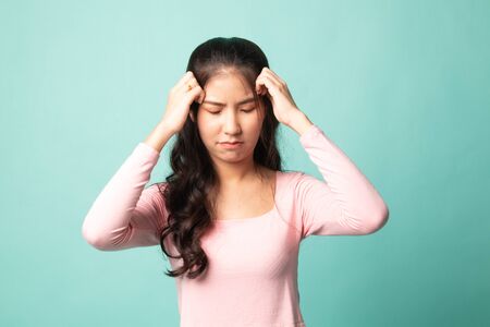 Young Asian woman got sick and  headache on cyan backgroundの写真素材
