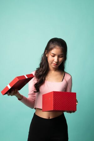 Young Asian woman open a gift box on cyan backgroundの写真素材