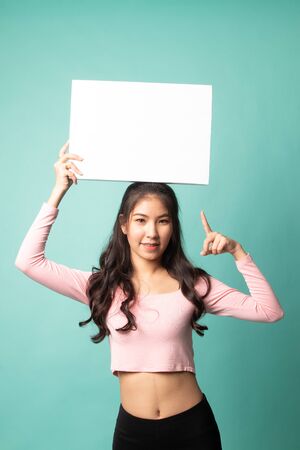 Young Asian woman point to blank sign on cyan backgroundの写真素材