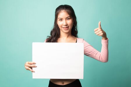 Young Asian woman show thumbs up with  white blank sign on cyan backgroundの写真素材