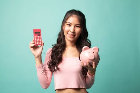 Asian woman with calculator and piggy bank on cyan backgroundの写真素材