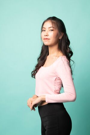 Portrait of beautiful young Asian woman on cyan backgroundの写真素材