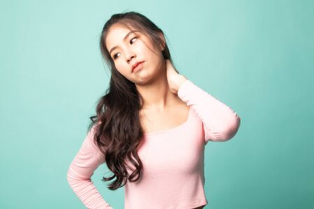 Young Asian woman got neck pain on cyan backgroundの写真素材