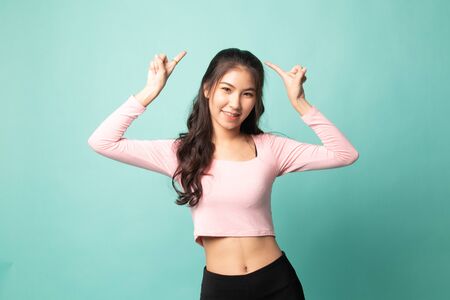 Young Asian woman point to blank space on cyan backgroundの写真素材