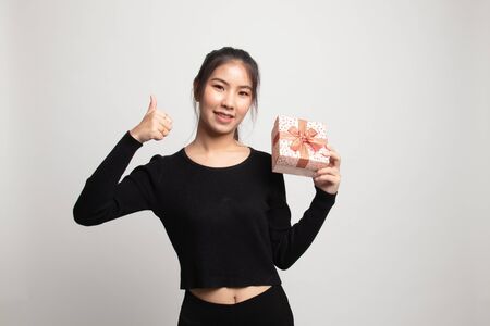 Asian woman thumbs up with a gift box on white backgroundの写真素材