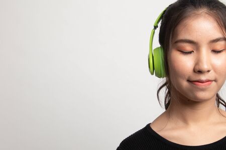 Pretty asian girl listening music with her headphones on white backgroundの写真素材