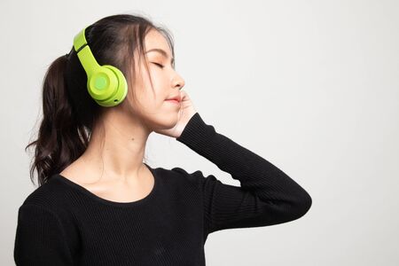 Pretty asian girl listening music with her headphones on white backgroundの写真素材