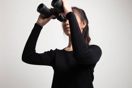 Young Asian woman with binoculars on white backgroundの写真素材
