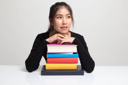 Happy young Asian woman read a book with books on table on white backgroundの写真素材