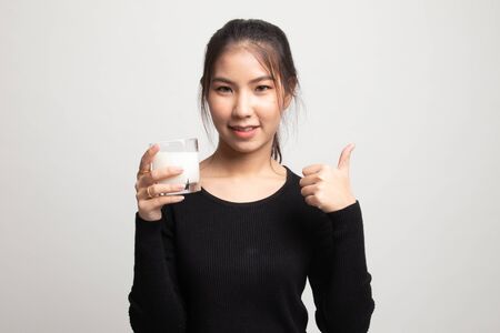 Healthy Asian woman drinking a glass of milk thumbs up on white backgroundの写真素材