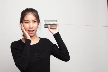 Happy Young Asian woman listen with tin can phone on white backgroundの写真素材