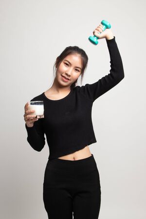 Healthy Asian woman drinking a glass of milk and dumbbell on white backgroundの写真素材