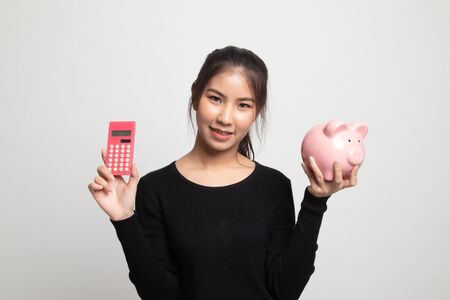 Asian woman with calculator and piggy bank on white backgroundの写真素材