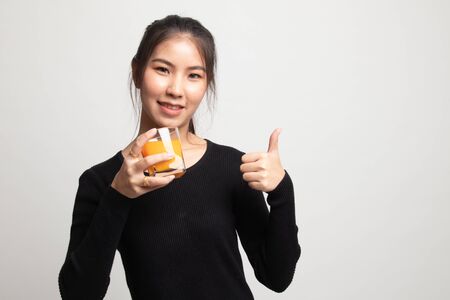 Young Asian woman thumbs up drink orange juice on white backgroundの写真素材
