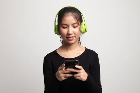 Pretty asian girl listening music with her headphones on white backgroundの写真素材