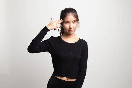 Beautiful young Asian woman holding fingers in gun gesture on white backgroundの写真素材