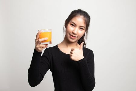 Young Asian woman thumbs up drink orange juice on white backgroundの写真素材