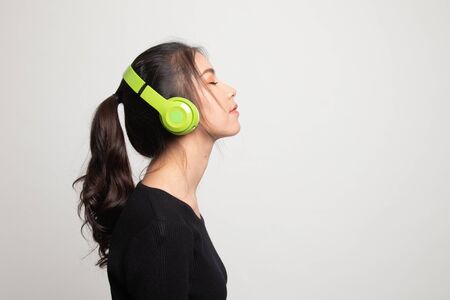 Pretty asian girl listening music with her headphones on white backgroundの写真素材