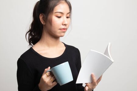 Young Asian woman with a book and cup of coffee on white background