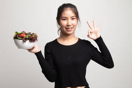 Healthy Asian woman show OK with salad on white backgroundの写真素材