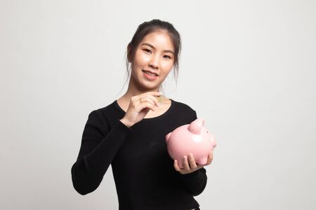 Asian woman with coin and pig coin bank on white backgroundの写真素材