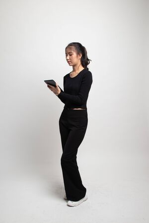 Full body of young Asian woman with a computer tablet on white backgroundの写真素材