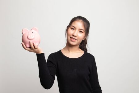 Young Asian woman with a pig coin bank on white backgroundの写真素材