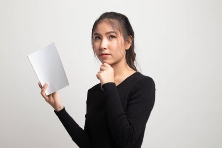 Young Asian woman with a book is thinking on white backgroundの写真素材