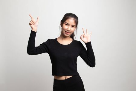 Young Asian woman point and show OK on white backgroundの写真素材