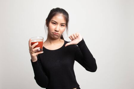Young Asian woman  thumbs down hate tomato juice on white backgroundの写真素材