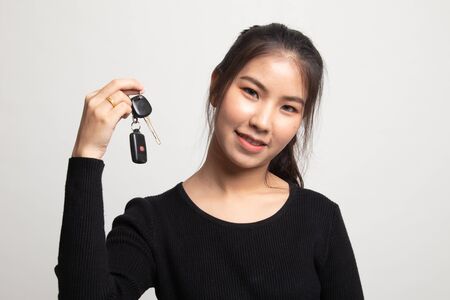 Cute asian girl showing home residence keys on white backgroundの写真素材
