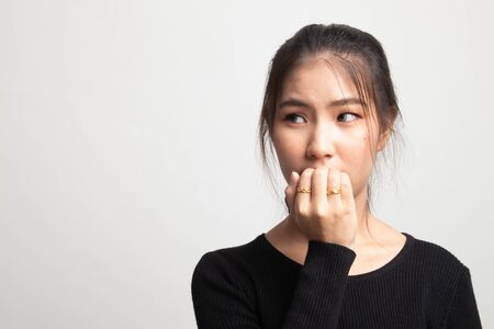 Unsure hesitant nervous young asian  woman biting her fingernails on white background