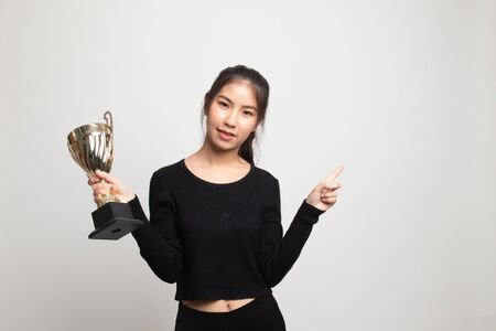 Successful young asian woman holding a trophy point to blank space on white backgroundの写真素材