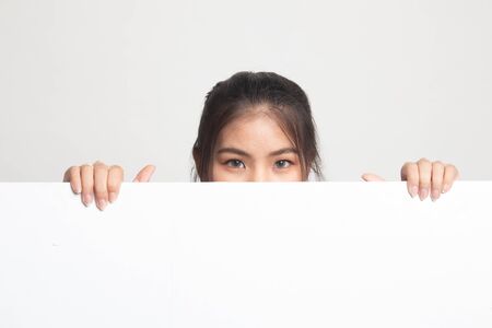 Close up of young Asian woman behind a blank sign on white backgroundの写真素材
