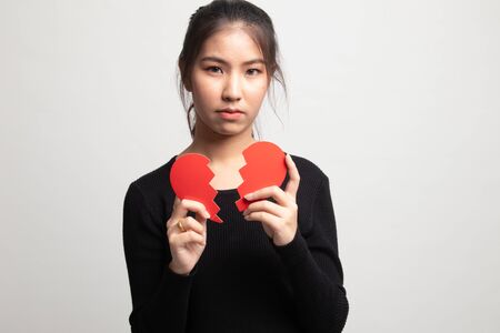 Beautiful young Asian woman with broken heart on white backgroundの写真素材