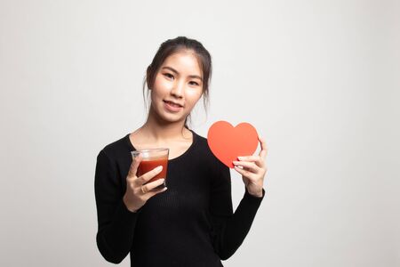 Young Asian woman with tomato juice and red heart on white backgroundの写真素材