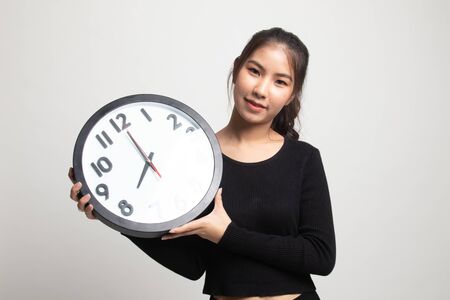 Young Asian woman with a clock on white backgroundの写真素材