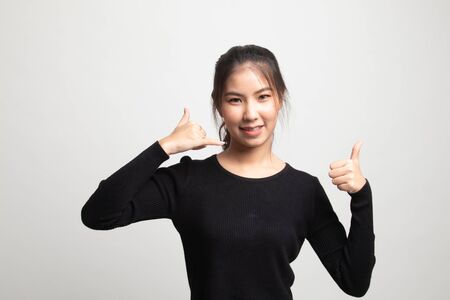 Young Asian woman thumbs up show with phone gesture on white backgroundの写真素材
