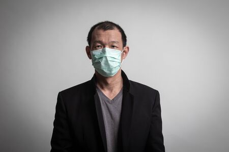 Asian man  wearing surgical  mask to prevent flu virus and  PM2.5 dust air pollution on white backgroundの写真素材