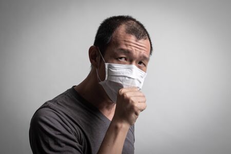 Sick Asian man coughing and  wearingsurgical  mask  to prevent flu virus and  PM2.5 dust air pollution on white backgroundの写真素材