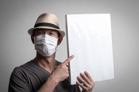 Asian man  wearing surgical  mask to prevent flu virus and  PM2.5 dust air pollution with white blank sign on white backgroundの写真素材