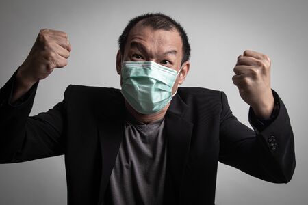 Angry Asian man  wearing surgical  mask to prevent flu virus and  PM2.5 dust air pollution on white backgroundの写真素材