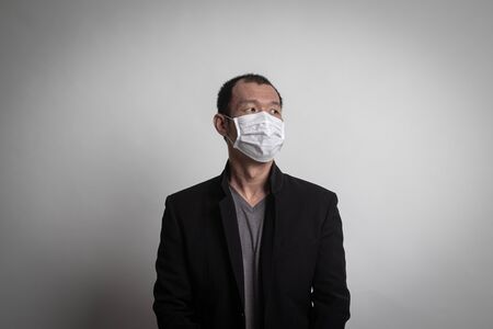 Asian man  wearing surgical  mask to prevent flu virus and  PM2.5 dust air pollution on white backgroundの写真素材