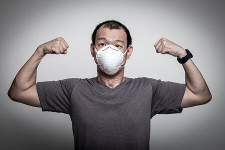 Strong Asian man wearing N95  mask to prevent flu virus and  PM2.5 dust air pollution on white backgroundの写真素材