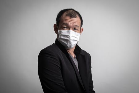 Asian man  wearing surgical  mask to prevent flu virus and  PM2.5 dust air pollution on white backgroundの写真素材